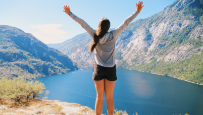 Girl with both arms in the air at a beautiful Yosemite overlook.