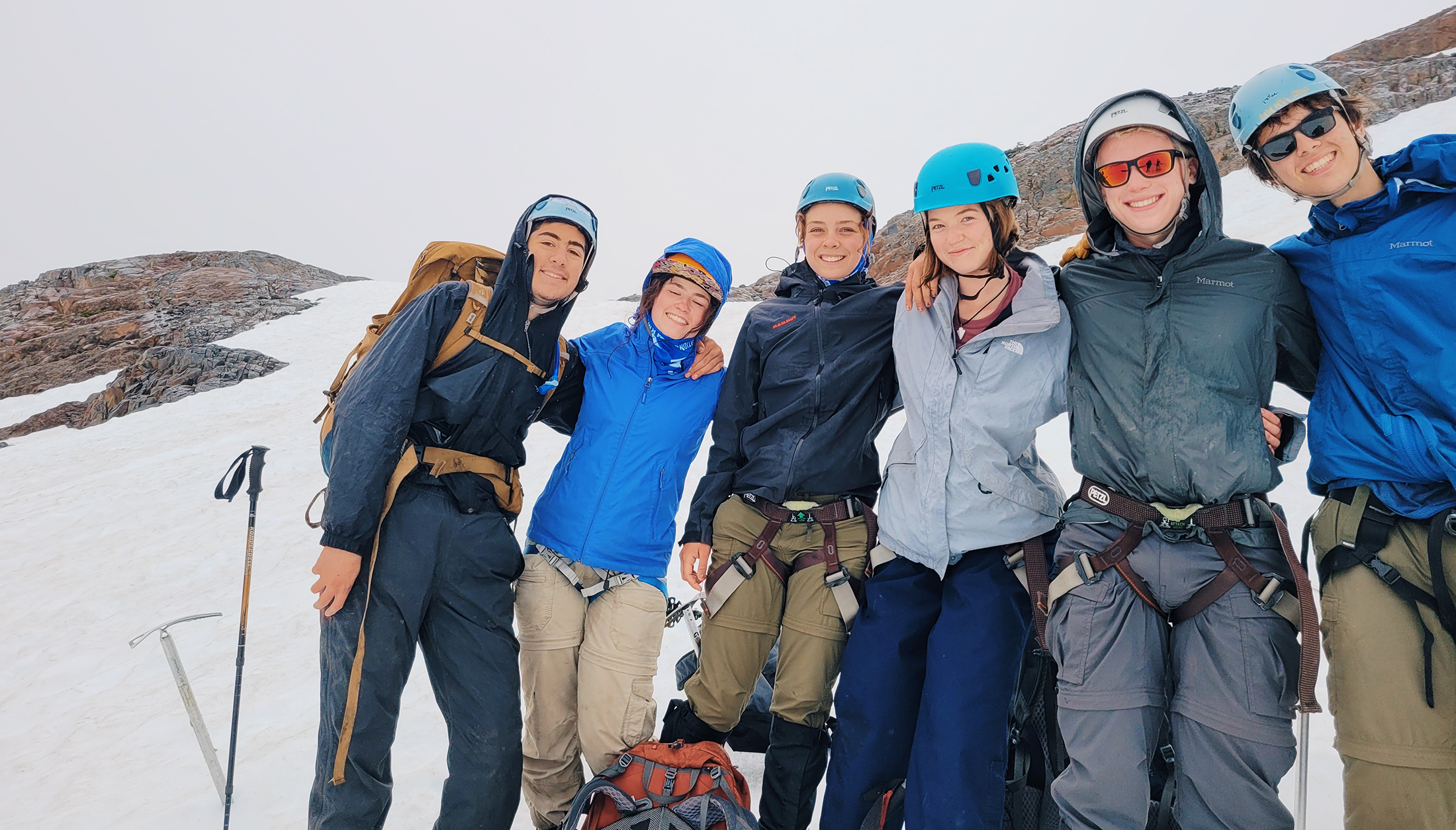 Six people mountaineering smiling together. 