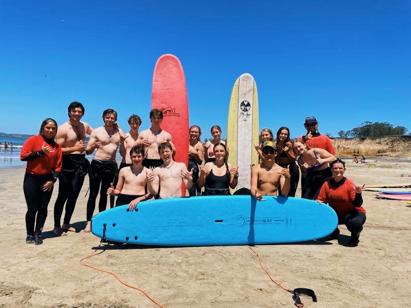 Group of people with surfboards on the beach. 