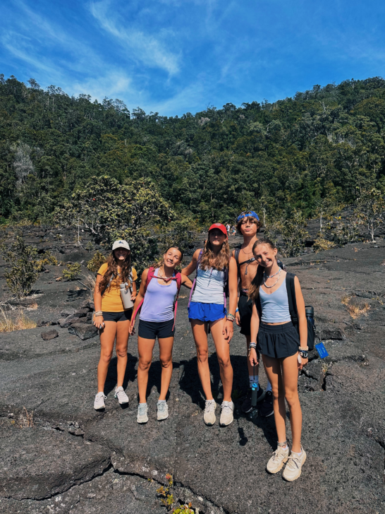 Group of young hikers hiking on volcanic rock in Hawaii.