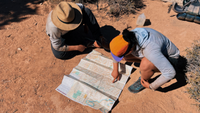 Two people looking at a map in the desert.