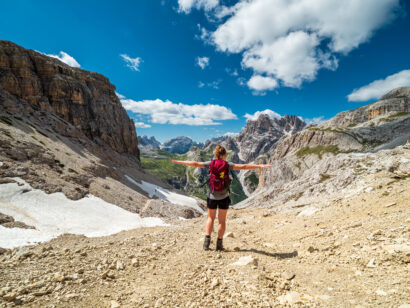 Girl with her arms out hiking in the Dolomite Mountains in Italy.