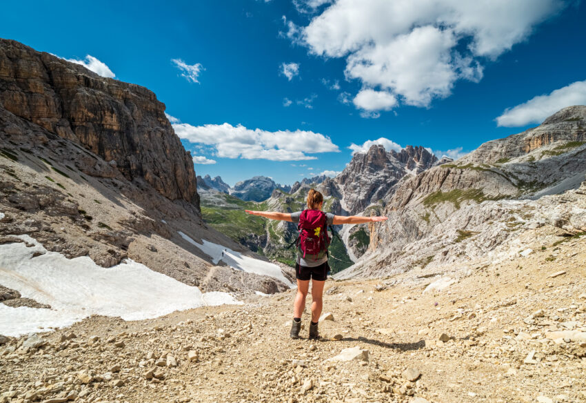 Girl with her arms out hiking in the Dolomite Mountains in Italy.