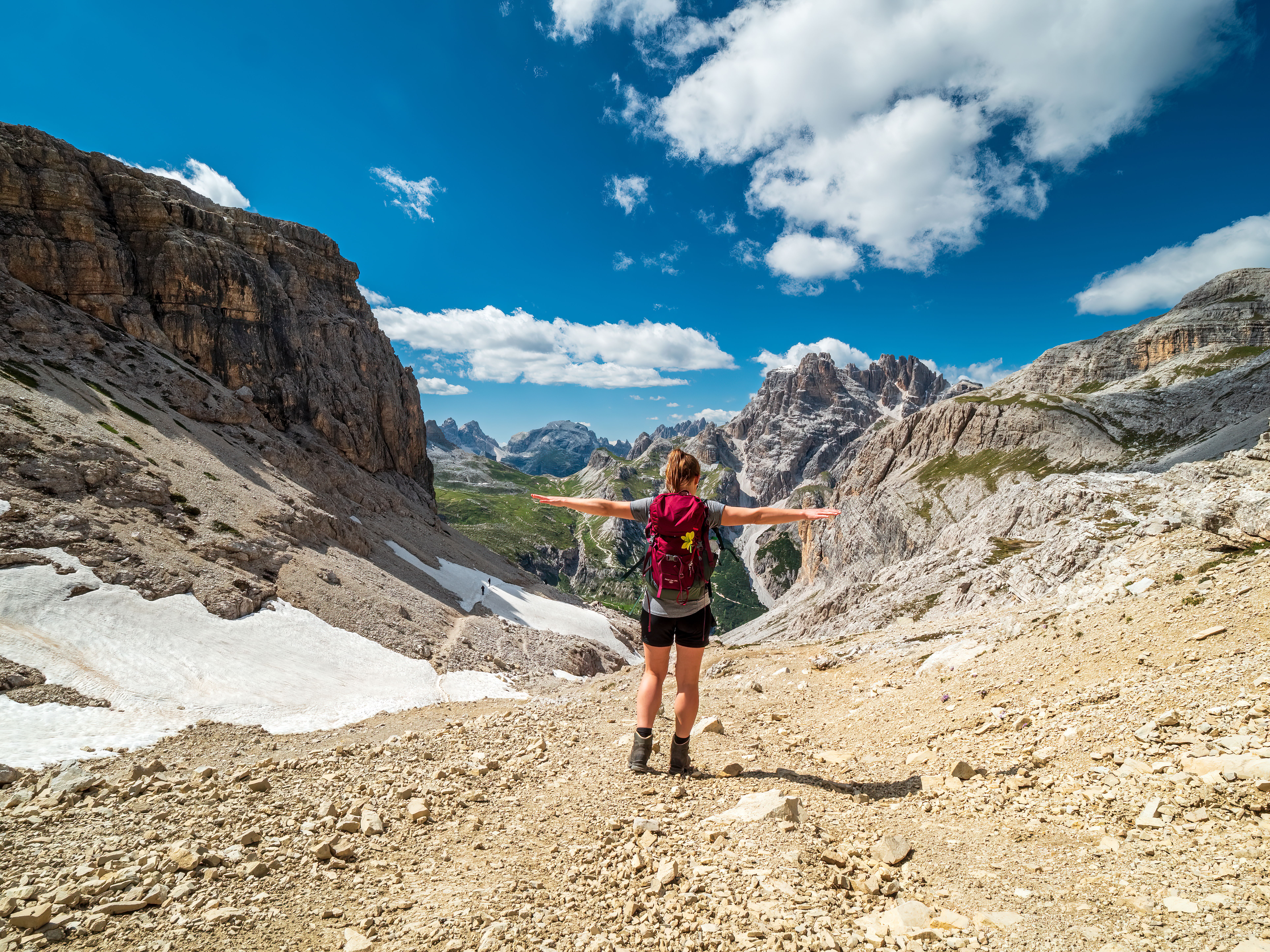 Girl with her arms out hiking in the Dolomite Mountains in Italy.